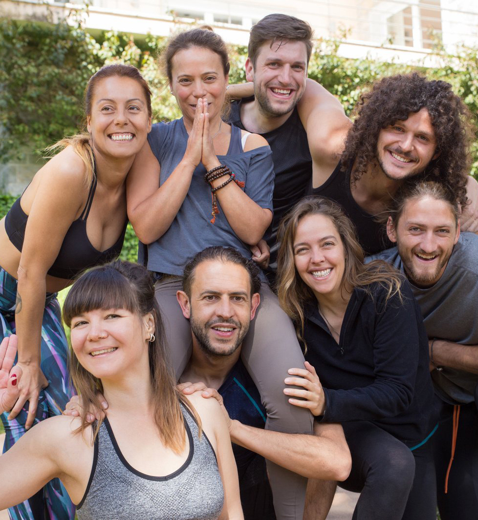 Many people in yoga clothes smiling and looking at the camera